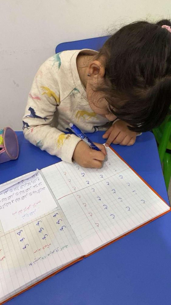 طفلة تكتب الحروف العربية في الكراس