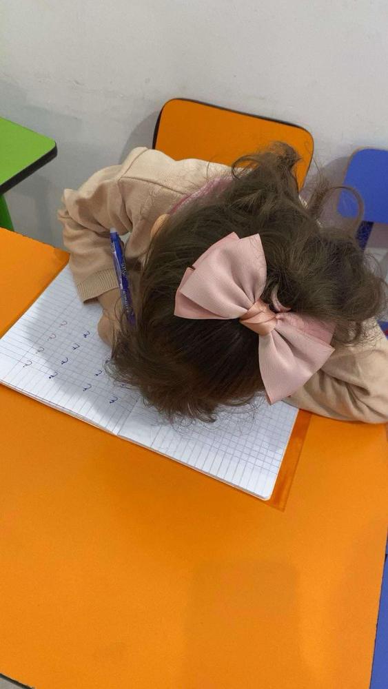 طفلة تكتب في كراس التمارين