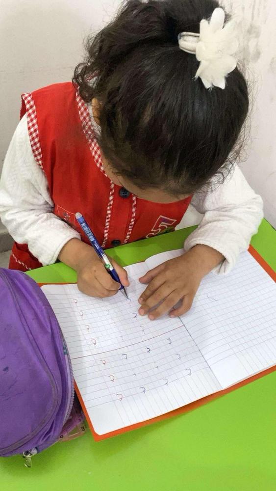 طفلة تتابع تمرين الكتابة