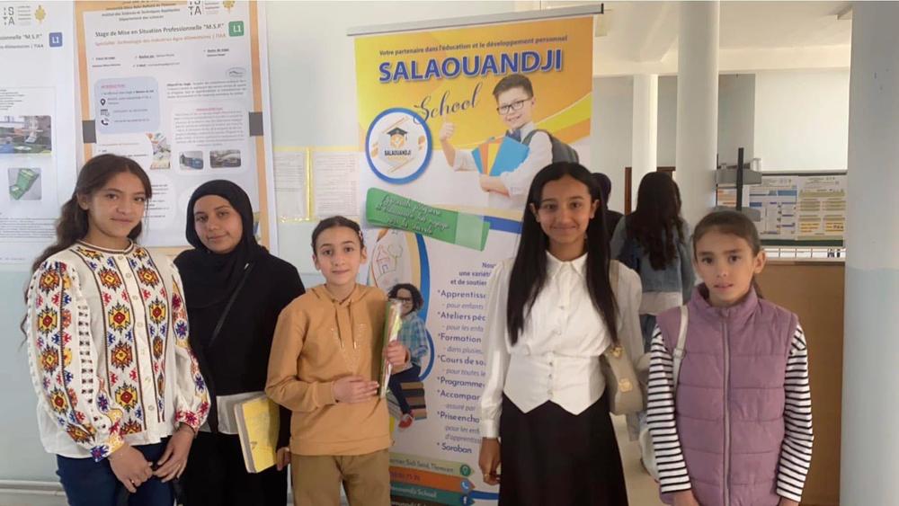 صورة جماعية أمام لافتة المدرسة